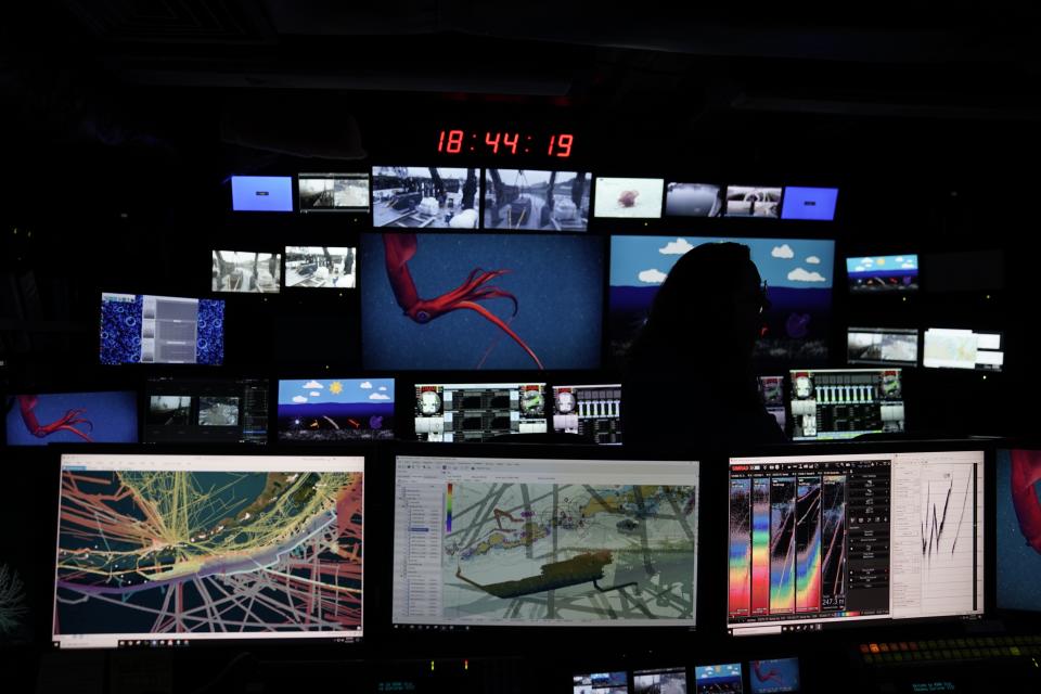 Shannon Hoy, an expedition coordinator, stands in front of control room screens inside the NOAA Okeanos Explorer, Friday, June 23, 2023, in Kodiak, Alaska. The ship, a reconfigured former U.S. Navy vessel run by civilians and members of the NOAA Corps, is specially outfitted with technology and tools needed to access deep into the ocean, and to share that data with the public and on-shore researchers in real-time. (AP Photo/Joshua A. Bickel)