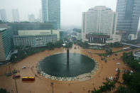 People struggle through floodwaters in Jakarta's central business district on January 17, 2013 in Jakarta, Indonesia. Thousands of Indonesians were displaced and the capital was covered in many key areas in over a meter of water after days of heavy rain. (Photo by Ed Wray/Getty Images)