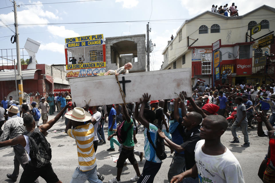 Protesters carry a symbolic coffin for President Jovenel Moise, as they march to call for his resignation in Port-au-Prince, Haiti, Friday, Oct. 4, 2019. Thousands of protesters marched through the Haitian capital to the U.N. headquarters Friday in one of the largest demonstrations in a weekslong push to oust the embattled president Jovenel Moise.(AP Photo/Rebecca Blackwell)