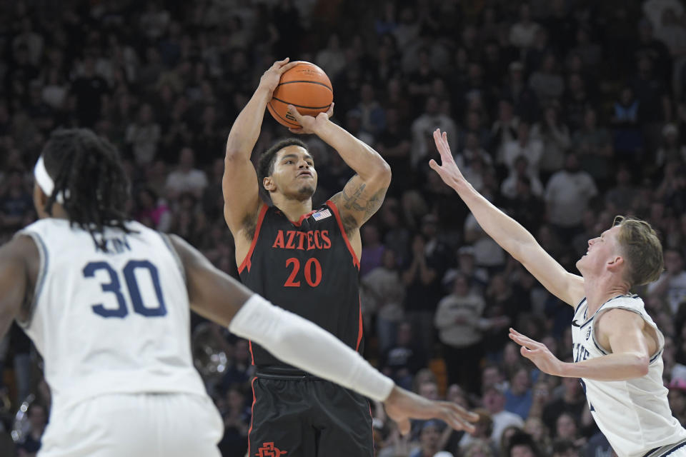 San Diego State guard Matt Bradley (20) shoots the ball as Utah State forward Dan Akin (30) and guard Sean Bairstow defend during the first half of an NCAA college basketball game Wednesday, Feb. 8, 2023, in Logan, Utah. (AP Photo/Eli Lucero)