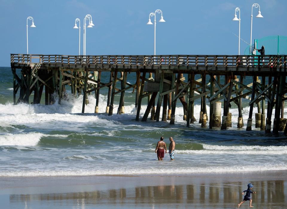 A pair of beachgoers watch as waves start to crash under the Daytona Pier on Monday in Daytona Beach, where the initial effects of Subtropical Storm Nicole were evident long before its expected approach on Wednesday. Volusia and Flagler county officials urged residents to prepare now.
