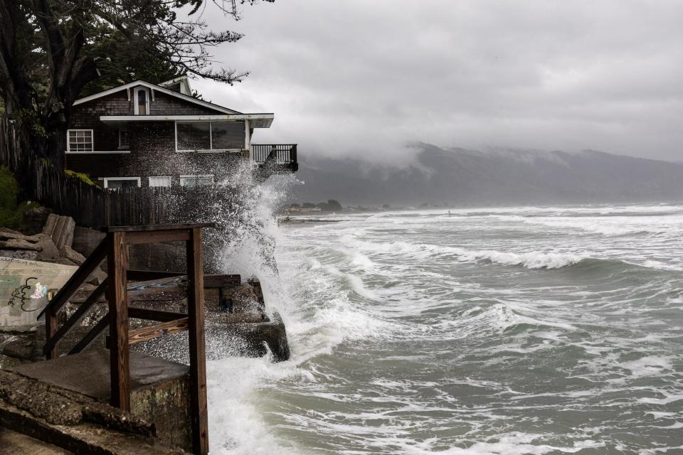 A large wave splashes onto a house on the California coast during an atmospheric river