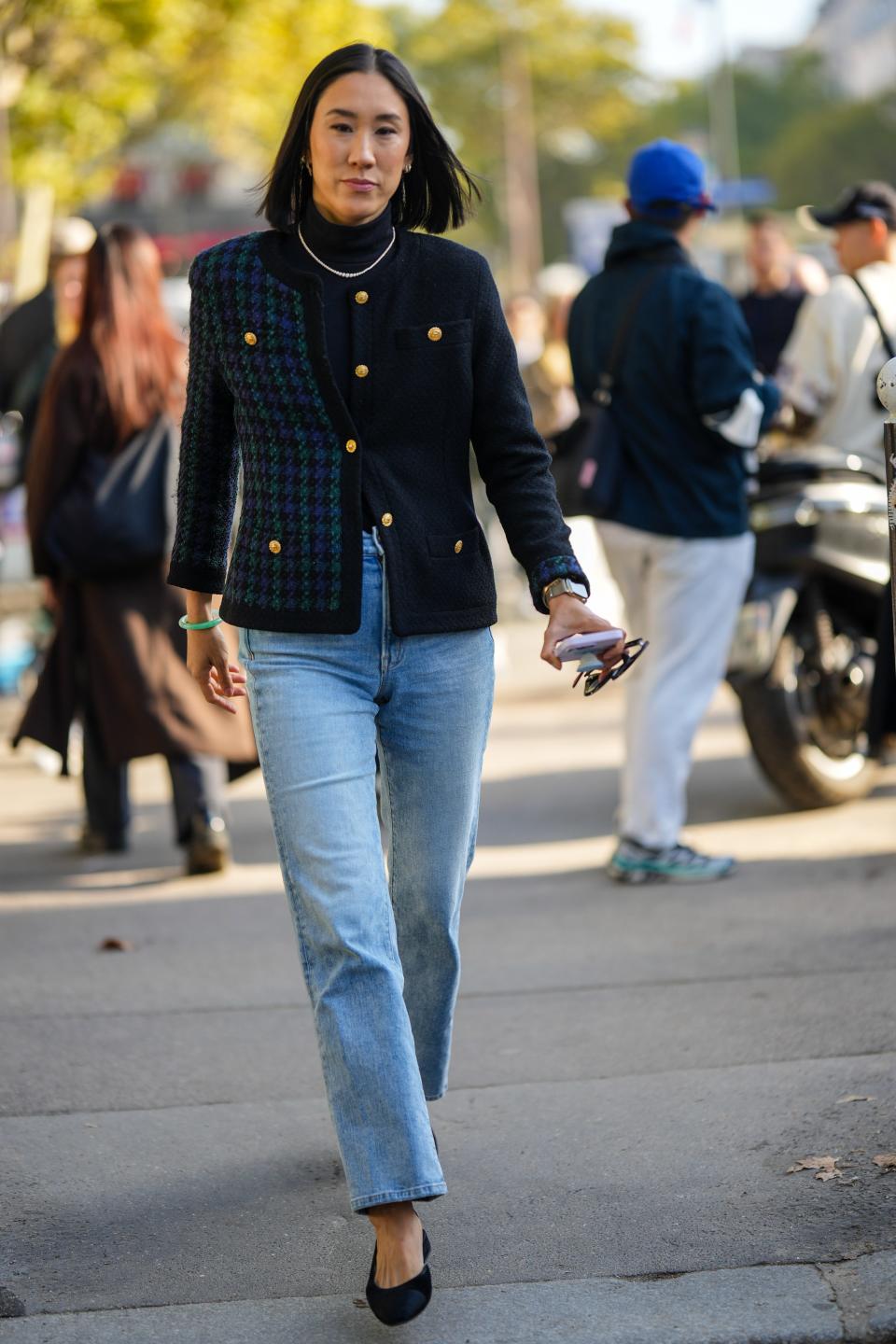 Eva Chen wearing blue jeans and a blue and green blazer with gold buttons.