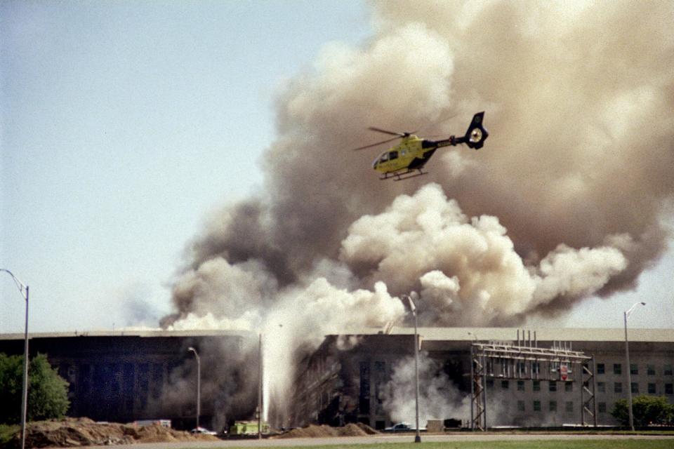 A helicopter flies over the Pentagon in Washington, Tuesday, Sept. 11, 2001 as smoke billows over the building. The Pentagon took a direct, devastating hit from an aircraft and the enduring symbols of American power were evacuated as an apparent terrorist attack quickly spread fear and chaos in the nation's capital.