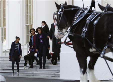 U.S. first lady Michelle Obama (front R) and her daughters Sasha (L) and Malia welcome the official White House Christmas tree at the North Portico of the White House in Washington, November 29, 2013. REUTERS/Jason Reed