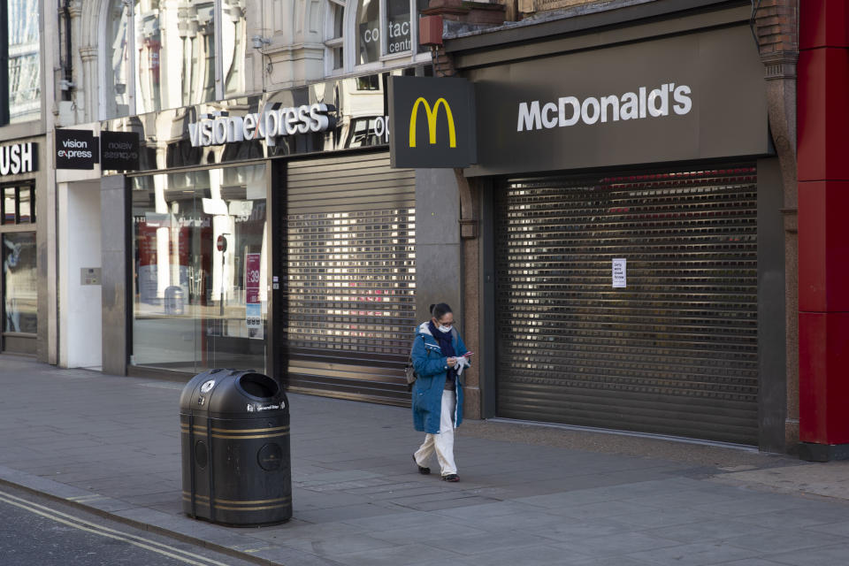 A woman in a face mask wasks past major shops on Oxford Street, closed for business. March 24th 2020 was the first day of enforced lockdown in the UK, in order to stop the spread of the Coronavirus Covid 19. On what would normally be a bustling business / week day in London, the city was deserted, with just a few people in masks out on the street, plus a few taxis and mostly empty buses. (photo by Phil Clarke Hill/In Pictures via Getty Images)