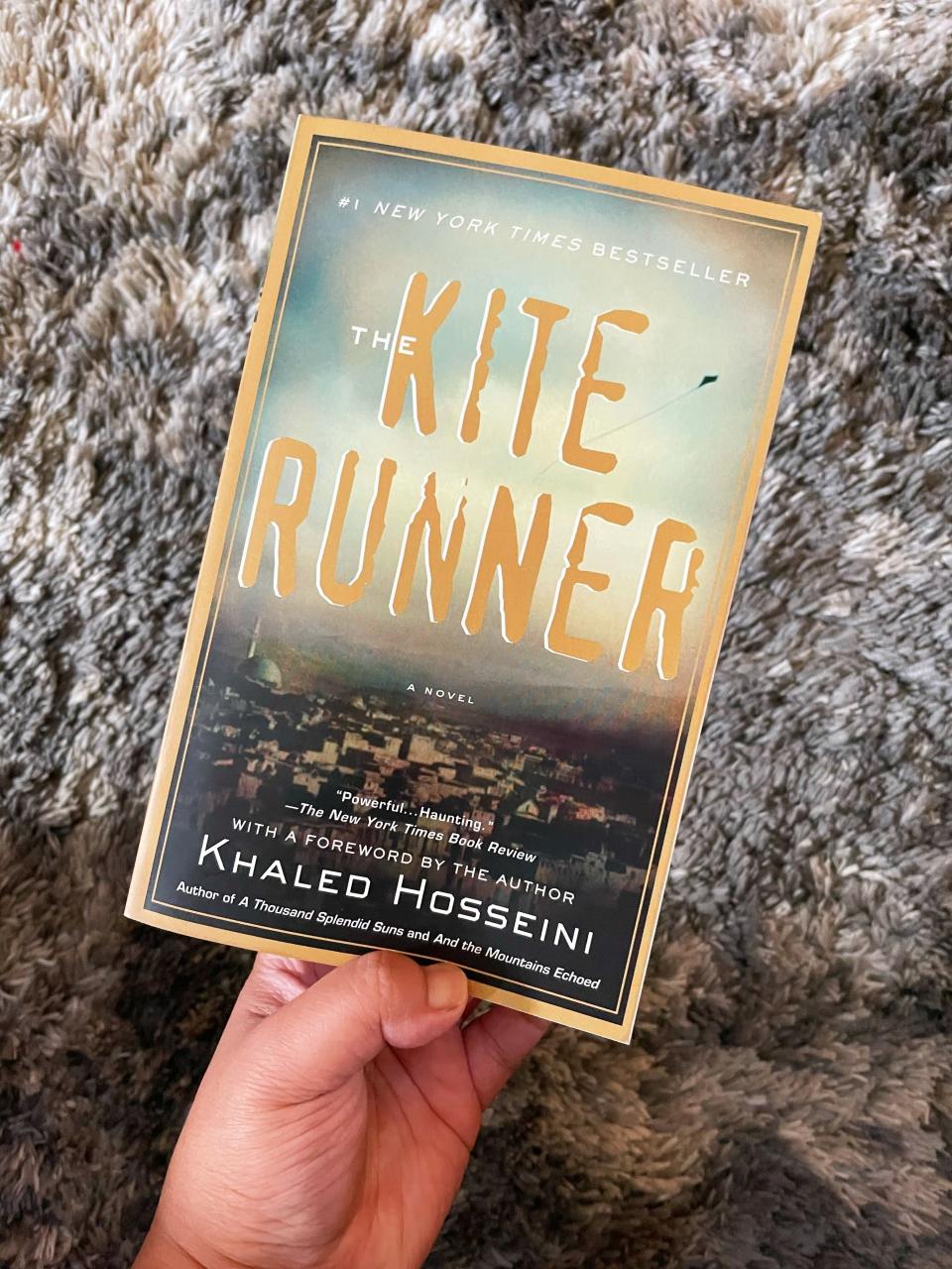 The author is holding a copy of Khaled Hosseini's "The Kite Runner"