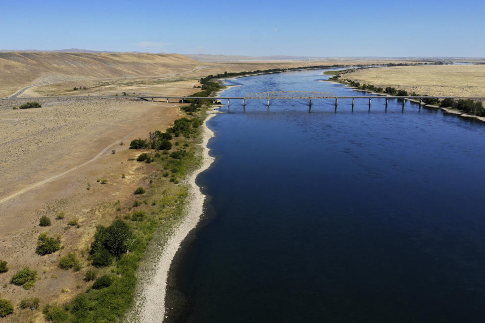In this Wednesday, Aug. 14, 2019 photo, the Columbia River flows under the Vernita Bridge and past the Hanford Reach National Monument, left, and the Hanford Nuclear Reservation, right beyond the bridge, near Richland, Wash. Washington state officials are worried that the Trump administration wants to reclassify millions of gallons of wastewater at Hanford from high-level radioactive to low-level, which could reduce cleanup standards and cut costs. (AP Photo/Elaine Thompson)