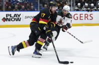 Vancouver Canucks' Filip Hronek (17) and Arizona Coyotes' Nick Schmaltz (8) vie for the puck during the third period of an NHL hockey game Wednesday, April 10, 2024, in Vancouver, British Columbia. (Ethan Cairns/The Canadian Press via AP)