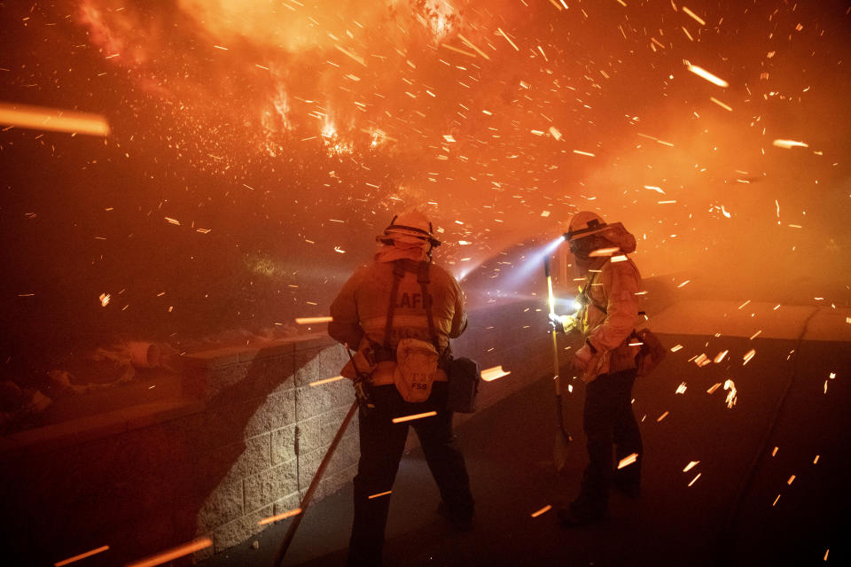 In this Thursday, Oct. 10, 2019 photo, embers from the Saddleridge fire blow by firefighters in Sylmar, Calif. (Photo: Michael Owen Baker/AP)