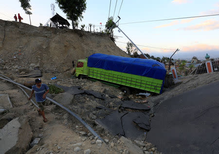 A man walks near a truck that was trapped inside sinking ground after an earthquake hit at Balaroa sub-district in Palu, Sulawesi Island. REUTERS/Beawiharta