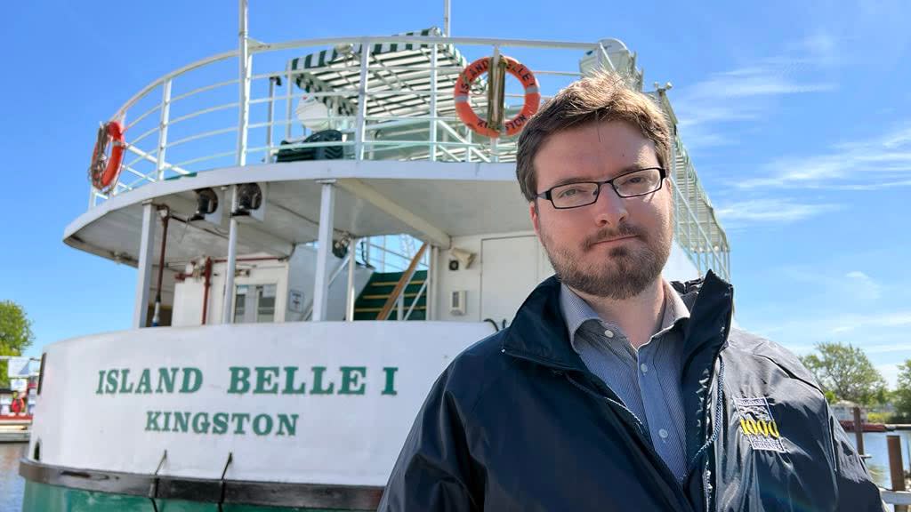 Kingston 1000 Islands Cruises general manager Eric Ferguson stands next to the Island Belle, which remains trapped on the wrong side of the LaSalle Causeway two months after its bridge was damaged. Ferguson is skeptical the department responsible for the causeway will offer any compensation to cruise ship businesses. (Dan Taekema/CBC - image credit)