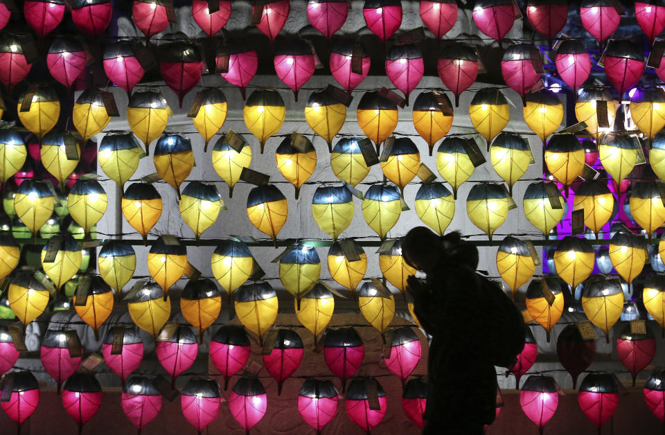 A woman prays in front of a wall of lanterns to celebrate the new year at the Jogyesa Buddhist temple in Seoul, South Korea