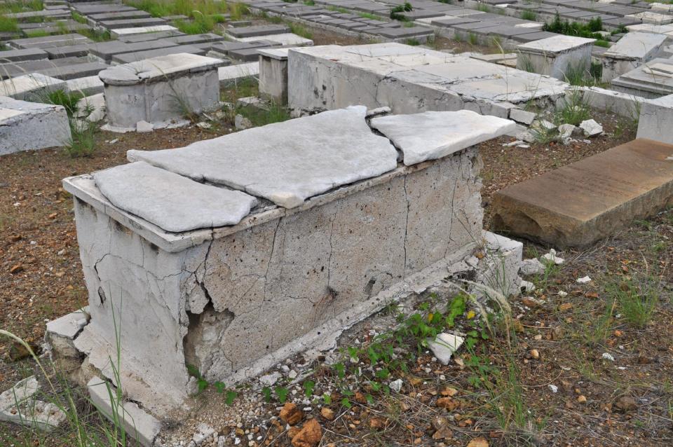 In this Nov. 12, 2012 photo, a crumbling tomb stands in the Beth Haim cemetery in Blenheim on the outskirts of Willemstad, Curacao. Beth Haim, believed to be one of the oldest Jewish cemeteries in the Western Hemisphere, established in the 1950s and considered an important landmark on an island where the historic downtown has been designated a UNESCO World Heritage Site, is slowly fading in the Caribbean sun. Headstones are pockmarked with their inscriptions faded, stone slabs that have covered tombs in some cases for hundreds of years are crumbling into the soil, marble that was once white is now grey, likely from the acrid smoke that spews from the oil refinery that looms nearby. (AP Photo/Karen Attiah)