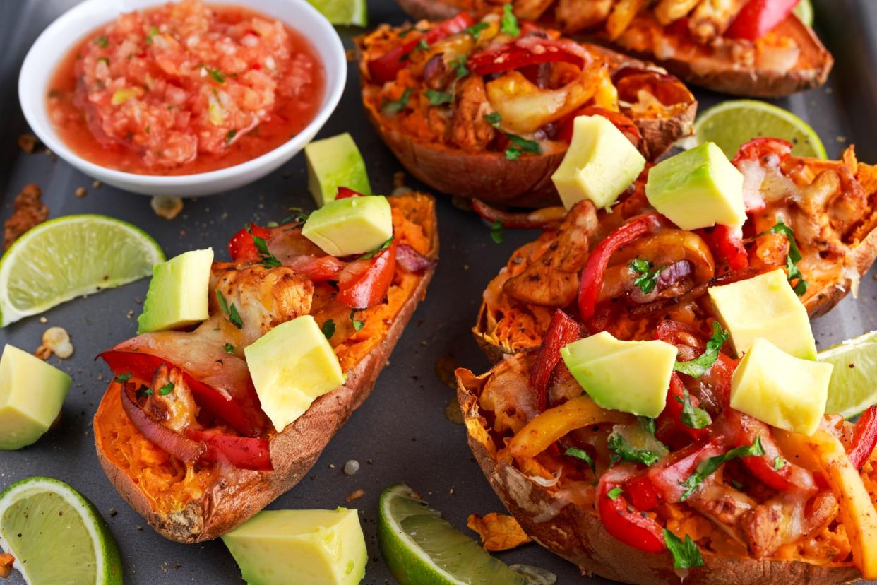 hot baked sweet potato stuffed with yellow, red pepper, chicken, cheese, herbs and salsa. selected focus.