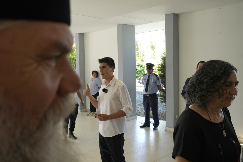 Orthodox priest, father Kiprianos, left, and the mother Eirini Panayiotou, right, of the popular YouTuber and TikToker with millions of online followers Fidias Panayiotou proclamation as the winner of one of six seats allotted to Cyprus in the European Parliament, arrive at the Filoxenia Conference Center in the capital Nicosia, Cyprus, on Tuesday, June 11, 2024. The 24-year-old Cypriot says he will continue using social media in his new job as a member of the European Parliament because he sees it as "my biggest weapon to use" in affecting the kind of change he wants to see on issues such as education. (AP Photo/Petros Karadjias)