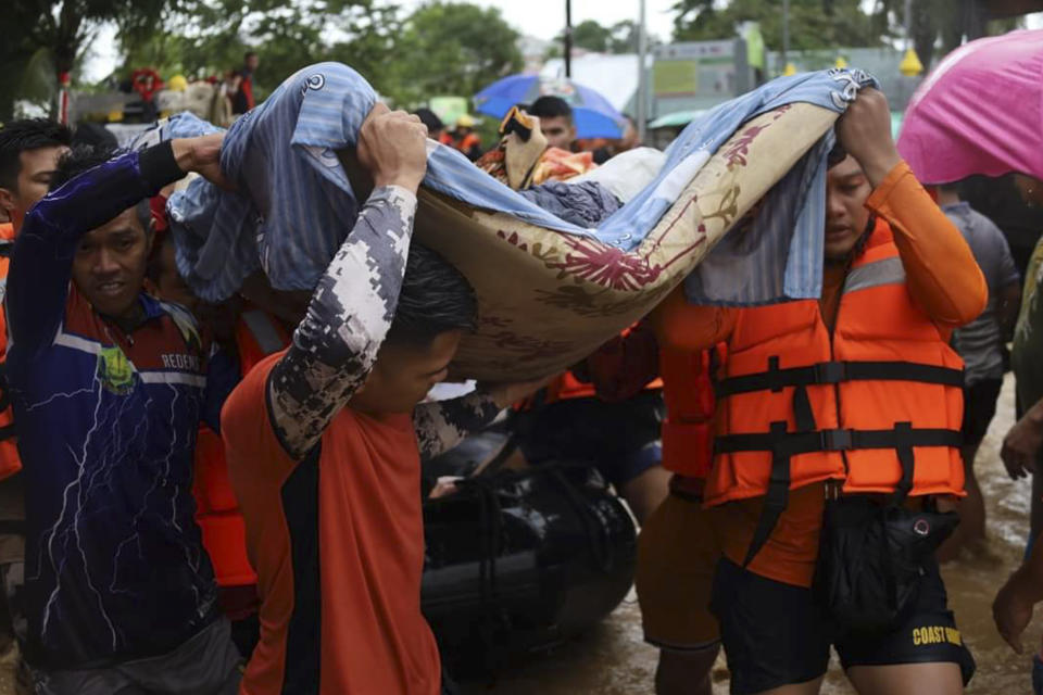 In this photo provided by the Philippine Coast Guard, rescuers carry a resident to safer grounds as floods rose due to Tropical Storm Nalgae at Parang, Maguindanao province, southern Philippines on Friday Oct. 28, 2022. (Philippine Coast Guard via AP)