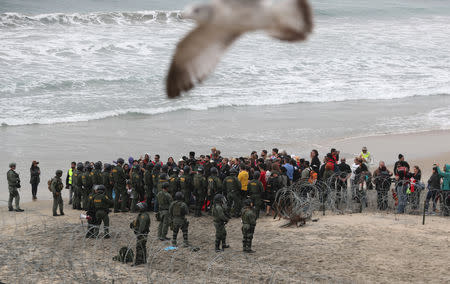 People take part in a gathering in support of the migrant caravan in San Diego, U.S., close to the border wall between the United States and Mexico, as seen from Tijuana, Mexico December 10, 2018. REUTERS/Mohammed Salem