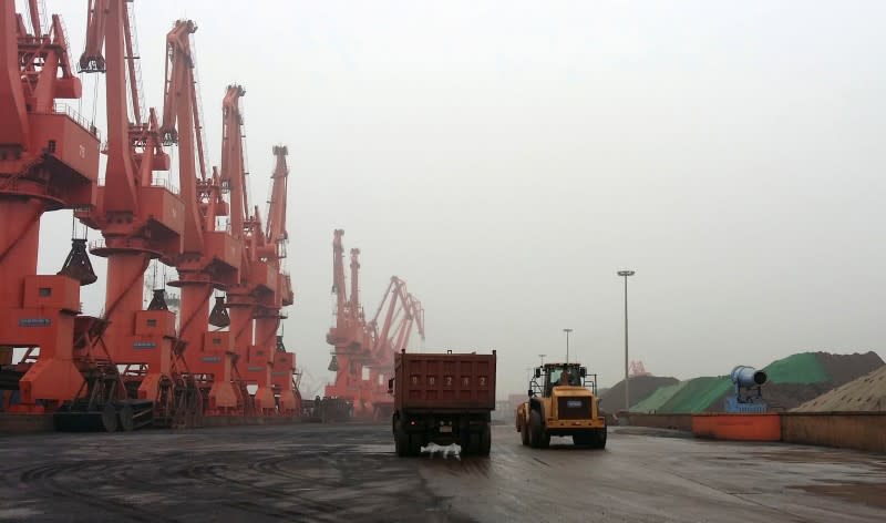 FILE PHOTO: Trucks drive inside an iron ore dump site at the Huanggang Terminal of Qingdao Port, in Qingdao, Shandong province June 7, 2014. REUTERS/Fayen Wong/File Photo