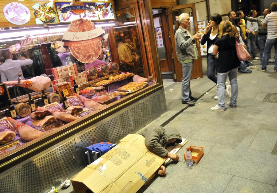 Una persona sin hogar frente a un bar en el centro de Madrid. <a href="https://www.shutterstock.com/es/image-photo/madrid-spain-may-2-2010-sleeping-588640484" rel="nofollow noopener" target="_blank" data-ylk="slk:Shutterstock / Bumble Dee;elm:context_link;itc:0;sec:content-canvas" class="link ">Shutterstock / Bumble Dee</a>