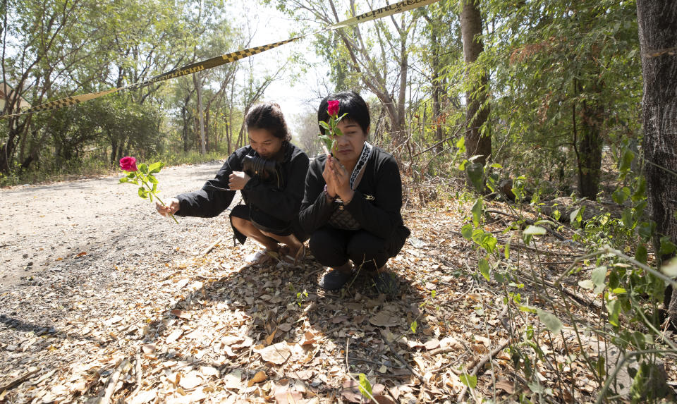 Mourners offer roses in condolence at the scene of the weekend's mass shooting that partially took place at the Wat Pa Sattharuam temple, Tuesday, Feb. 11, 2020, in Nakhon Ratchasima, Thailand. A rogue Thai soldier whose rampage left 29 people dead and dozens more injured terrorized a Buddhist temple complex in rural northeastern Nakhon Ratchasima province on his way to a shopping mall, where he held shoppers hostage in a nearly 16-hour siege. (AP Photo/Sakchai Lalit)