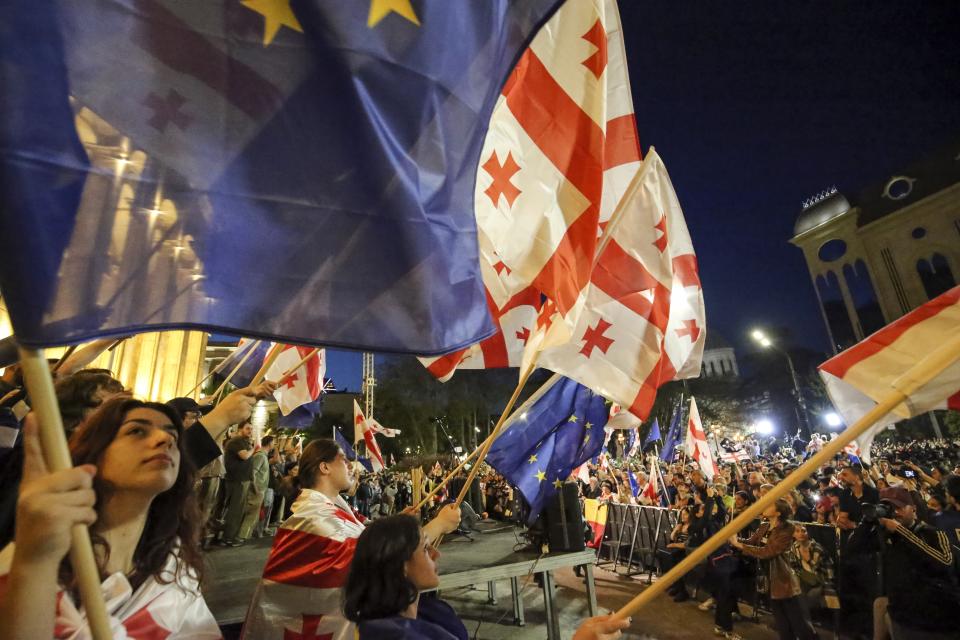 Demonstrators wave Georgian and EU flags as they gather outside the parliament building in Tbilisi, Georgia, on Wednesday, April 17, 2024, to protest against "the Russian law" similar to a law that Russia uses to stigmatize independent news media and organizations seen as being at odds with the Kremlin. (AP Photo/Zurab Tsertsvadze)