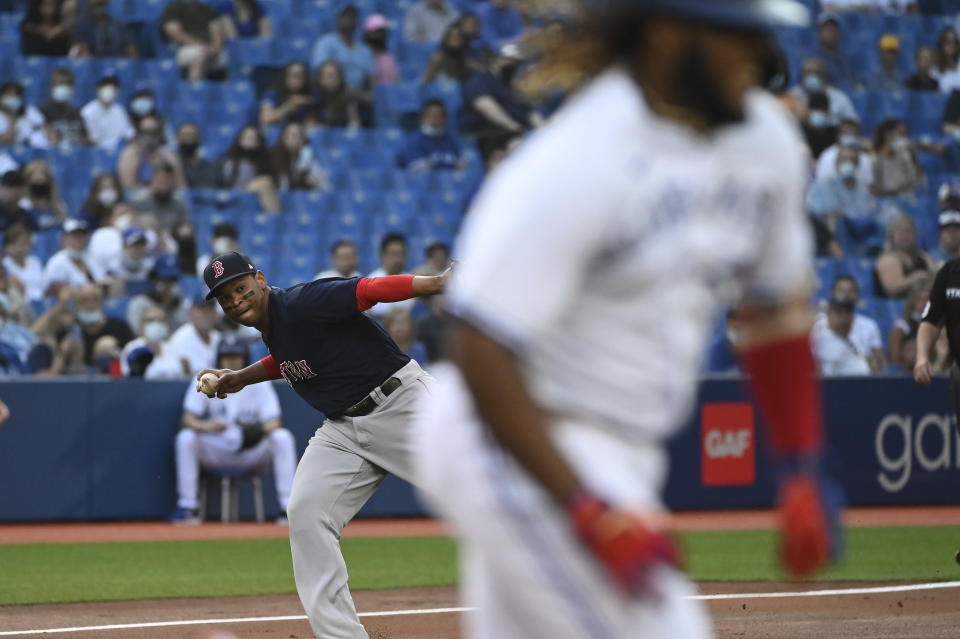 Boston Red Sox third baseman Rafael Devers, left, throws to first base but not in time to put out Toronto Blue Jays' Vladimir Guerrero Jr., right, in the first inning of the second game of a baseball doubleheader in Toronto, Saturday Aug. 7, 2021. (Jon Blacker/The Canadian Press via AP)