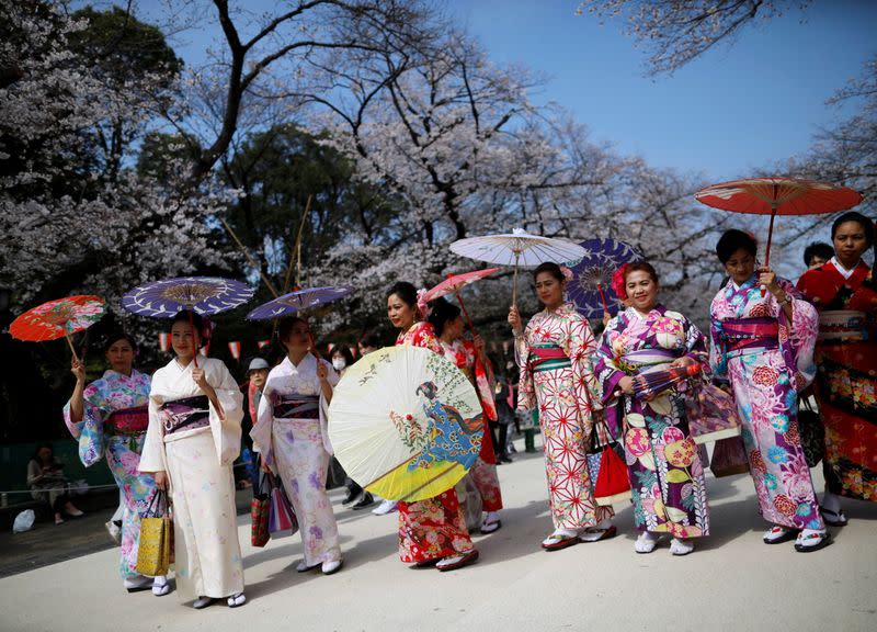 FILE PHOTO: Visitors from abroad wearing kimono clothes look at blooming cherry blossoms at Ueno park in Tokyo, Japan