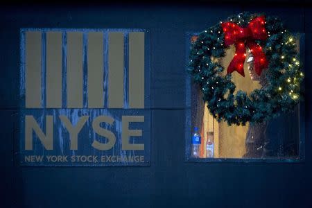 A police officer is pictured though a wreath as he stands guard in the rain at the New York Stock Exchange on the last day of trading before Christmas in the Manhattan borough of New York, December 24, 2014. REUTERS/Carlo Allegri