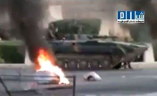 An image grab from a video uploaded on YouTube shows a Syrian army tank driving past burning tires in the city of Hama on July 31. Note: AFP is not authorized to cover this event and is therefore using pictures from alternative sources, which cannot be independently verified