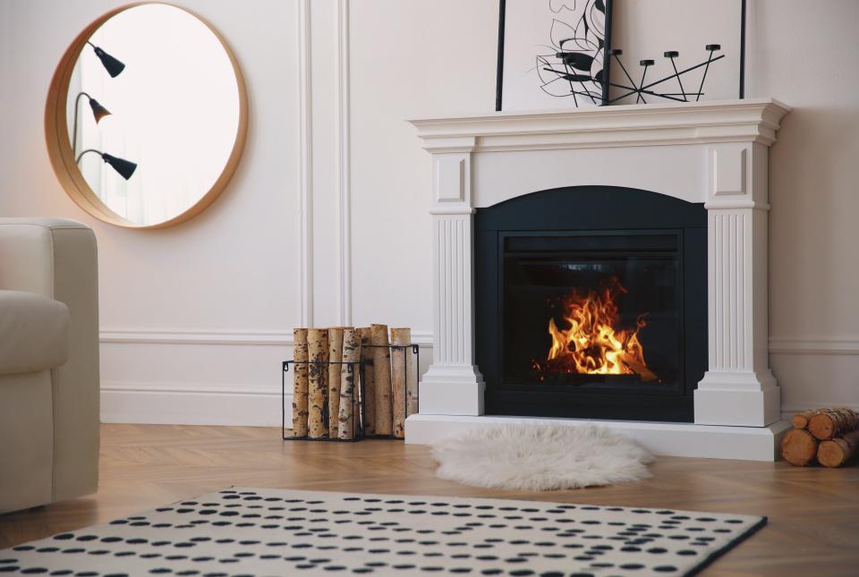 round mirror and white faux fireplace in room