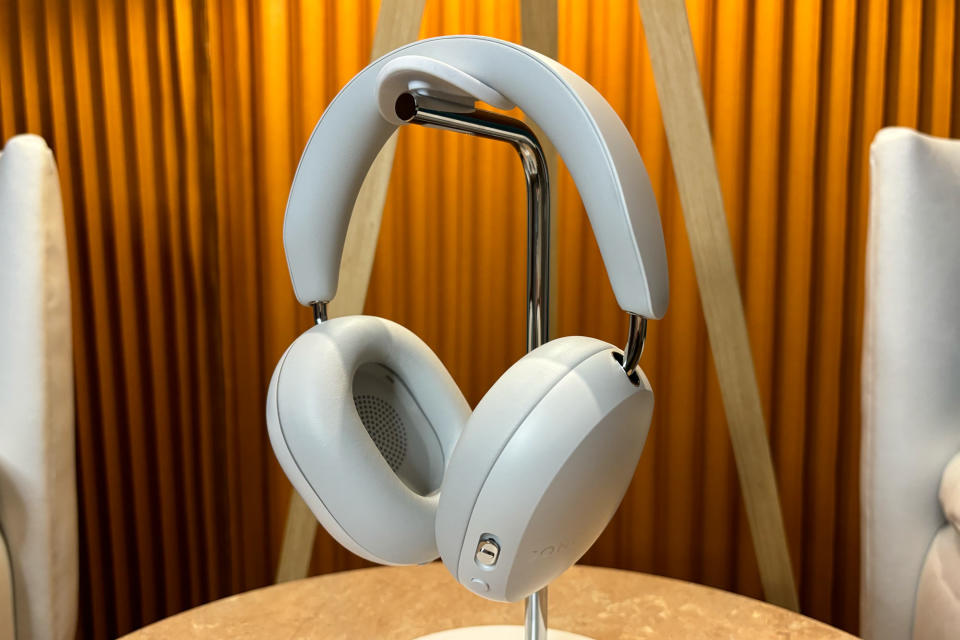 <p>White headphones on stand sitting on a small table.</p>
