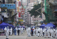 Government investigators wearing protective suits gather in the Yau Ma Tei area in Hong Kong, Saturday, Jan. 23, 2021. Thousands of Hong Kong residents were locked down Saturday in an unprecedented move to contain a worsening outbreak in the city, authorities said. (AP Photo/Vincent Yu)