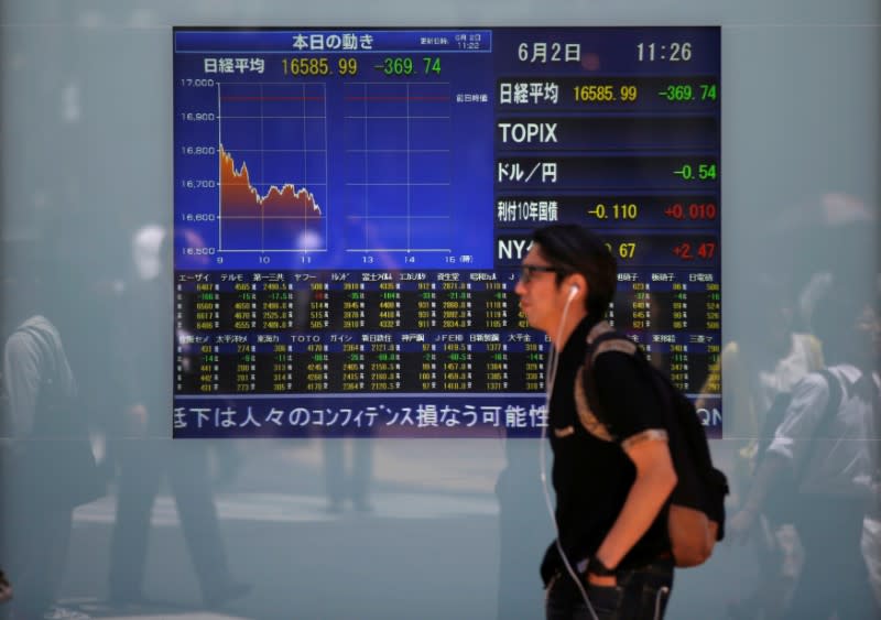 A man walks in front of a screen showing today's movements of Nikkei share average outside a brokerage in Tokyo, Japan, June 2, 2016. REUTERS/Issei Kato