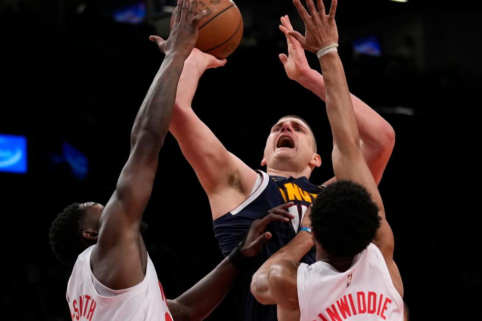 Brooklyn Nets' Dorian Finney-Smith, left, and Spencer Dinwiddie, right, defend Denver Nuggets' Nikola Jokic during the first half of an NBA basketball game Sunday, March 19, 2023, in New York. (AP Photo/Seth Wenig)