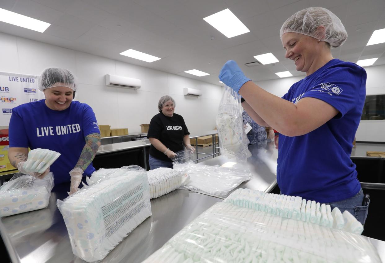 Theresa Cross, left, of Appleton; Nicolle Lorbiecki, center, of Menasha; and Tracy Fahrenkrug of New London collaborate to repackage donated diapers for the Kimberly-Clark Diaper Bank at the United Way Fox Cities Hub at VPI, Inc. in Appleton.