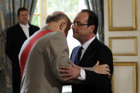 François Hollande reçoit l'insigne de Grand maître de l'Ordre de la Légion d'honneur avant de signer un registre avant de se rendre, entouré du président du Sénat et du président de l'Assemblée nationale, dans la salle des fêtes où l'attendent tous ses invités. AFP