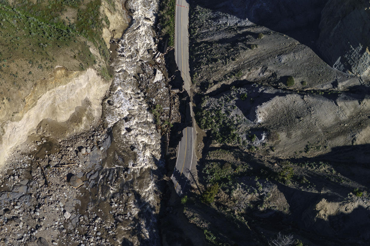 Receding floodwaters flow past sections of North Entrance Road washed away at Yellowstone National Park in Gardiner, Mont., Thursday, June 16, 2022. Yellowstone officials are hopeful that next week they can reopen the southern half of the park, which includes Old Faithful geyser. Park officials say the northern half of the park, however, is likely to remain closed all summer, a devastating blow to the local economies that rely on tourism. (AP Photo/David Goldman)