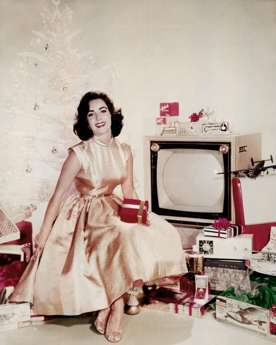 <p>The actress is the picture of Christmas in this 1955 advert, in which she poses next to a modern Christmas tree amongst dozens of presents. </p>