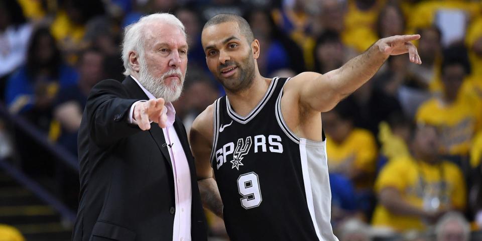 Tony Parker and Gregg Popovich stand side by side and point during a Spurs game in 2018.