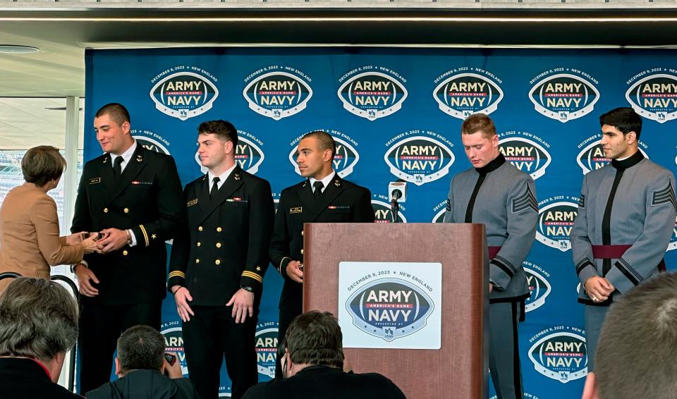 Massachusetts Gov. Maura Healey presents players with replicas of Paul Revere bowls to welcome them to the state for the Army-Navy game during a news conference at Gillette Stadium in Foxborough, Mass., on Nov. 29, 2023. From left are players: Navy defensive end Jacob Busic, linebacker Will Harbour, quarterback Xavier Arline, Army linebacker Leo Lowin, and defensive back Jimmy Ciarlo.