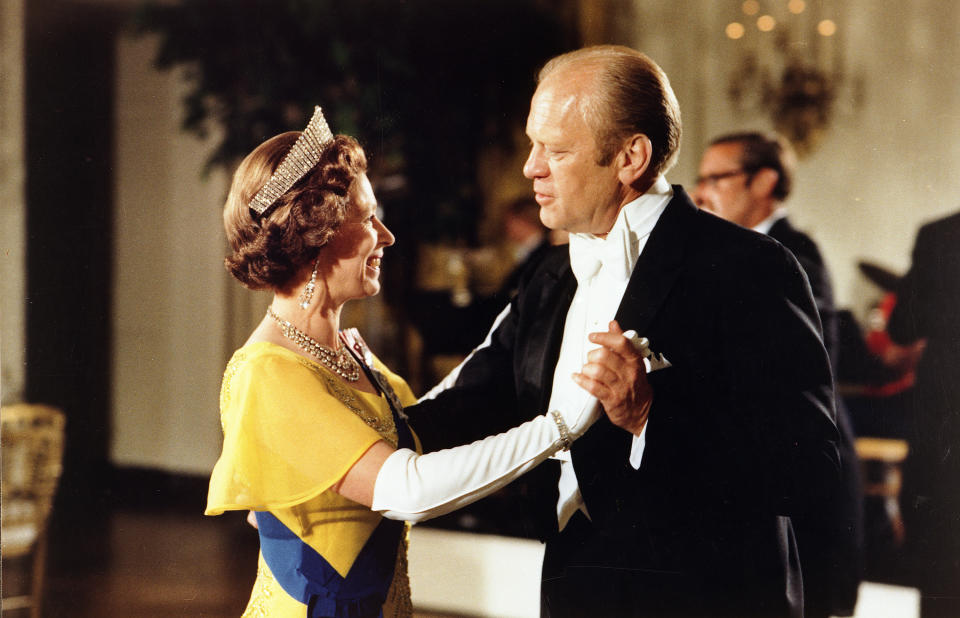 The queen, in tiara and wearing the Order of the Garter, dances with President Gerald Ford.