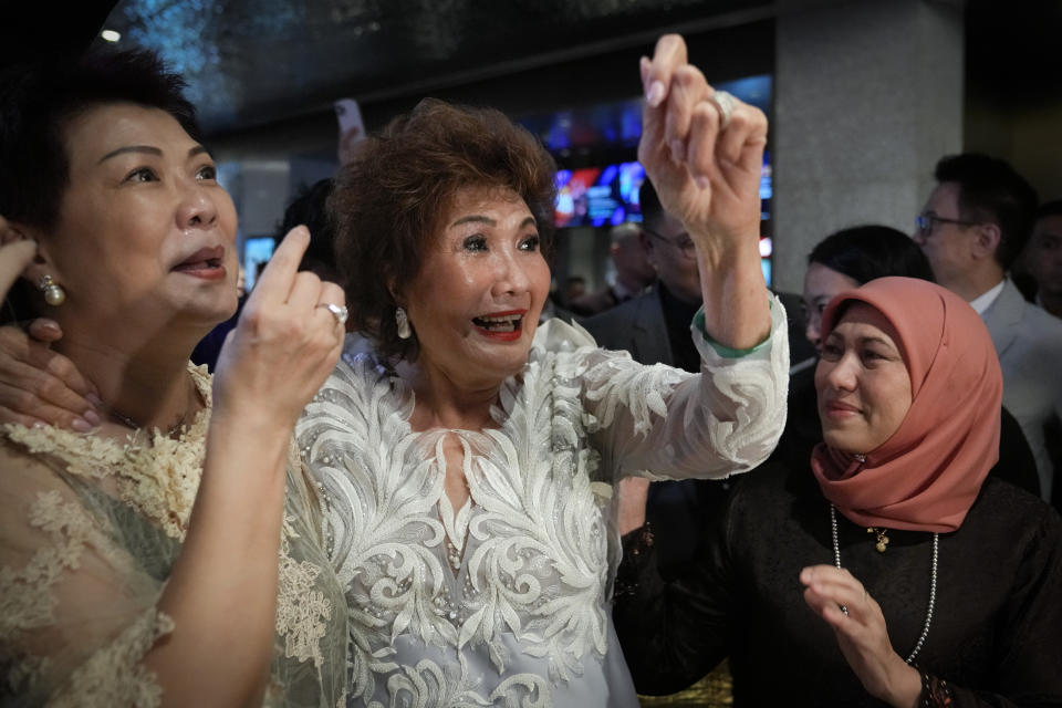 Janet Yeoh, center, mother of Michelle Yeoh, celebrates after her daughter won in the best actress category during the 95th Academy Awards in Los Angeles, as seen in a live view event at a cinema in Kuala Lumpur, Malaysia, Monday, March 13, 2023. (AP Photo/Vincent Thian)