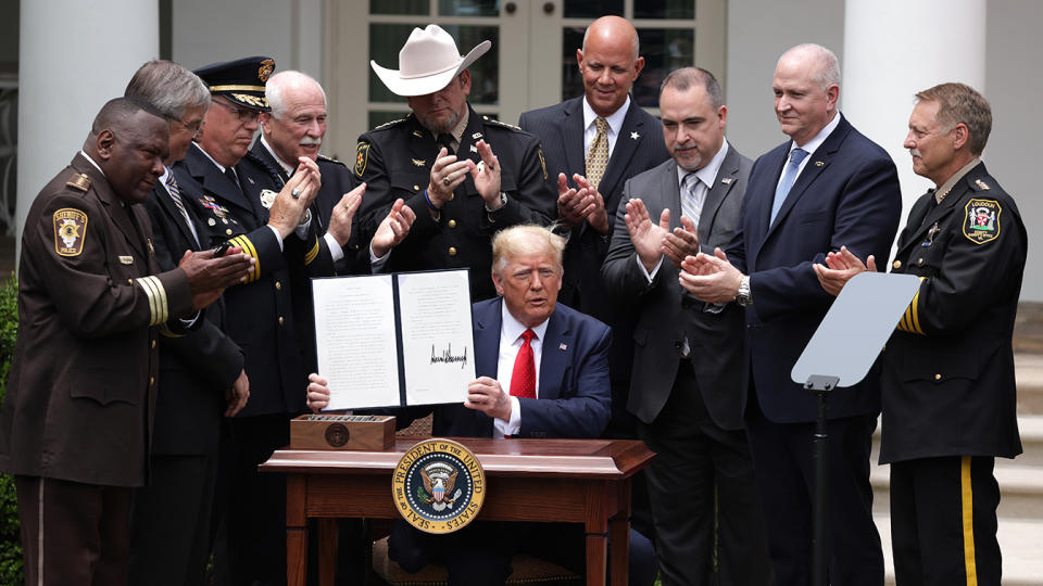 Surrounded by members of law enforcement, U.S. President Donald Trump holds up an executive order in the Rose Garden at the White House June 16, 2020.(Photo by Alex Wong/Getty Images)