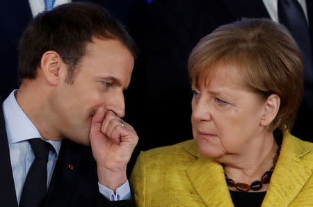 FILE PHOTO: French President Emmanuel Macron and German Chancellor Angela Merkel take part in a group photo on the launching of the Permanent Structured Cooperation, or PESCO, a pact between 25 EU governments to fund, develop and deploy armed forces together, during a EU summit in Brussels, Belgium, December 14, 2017. REUTERS/Yves Herman/File Photo