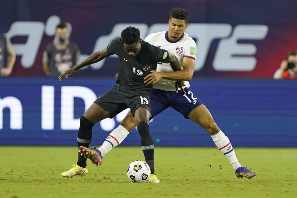 Canada defender Alphonso Davies (19) and United States' Miles Robinson (12) battle for the ball during the first half of a World Cup soccer qualifier Sunday, Sept. 5, 2021, in Nashville, Tenn. (AP Photo/Mark Humphrey)
