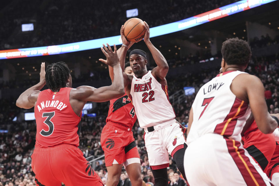 Miami Heat's Jimmy Butler makes a pass around Toronto Raptors' O.G. Anunoby, left, during the second half of an NBA basketball game, Wednesday, Dec. 6, 2023 in Toronto. (Chris Young/The Canadian Press via AP)