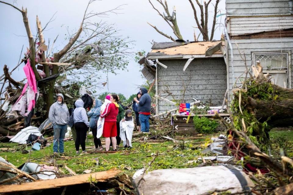 People gather to assess the damage as debris surrounds them
