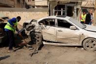 Baghdad municipality workers clean up as civilians inspect the site of a car bomb attack near the Technology University in Sinaa Street in downtown Baghdad, Iraq, Wednesday, Jan. 15, 2014. A wave of bombings across Iraq striking busy markets and a funeral north of Baghdad killed tens of people Wednesday, authorities said, as the country remains gripped by violence after al-Qaida-linked militants took control of two cities in western Anbar province. (AP Photo/Karim Kadim)