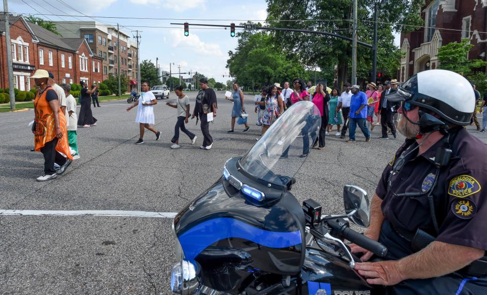 June 9 2024; Tuscaloosa, AL, USA; Marchers commemorating the 60th anniversary commemoration of the Bloody Tuesday event in Tuscaloosa walk past a Tuscaloosa Police officer who is blocking an intersection. Sixty years ago, law enforcement officers and a deputized mob beat and arrested civil rights marchers who were walking to the courthouse to protest the inclusion of segregated facilities.